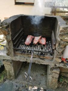 three pieces of meat cooking on a grill at La Albarina in Galende