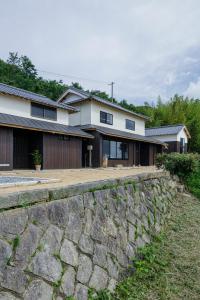 una casa con una pared de piedra delante de ella en kotobukian 寿庵, en Awaji