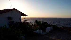 a house with the sun setting over the ocean at Muses sea view bungalow in Armenistis