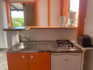 a small kitchen with a sink and a stove at Bungalow les Cerisiers in Bouillante