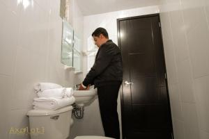 a man standing in a bathroom with a sink at Hotel Y Suites Axolotl in Chignahuapan