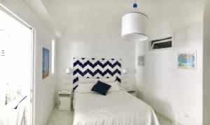 a white bedroom with a bed with a blue and white headboard at Marilù vacation home in Positano in Positano