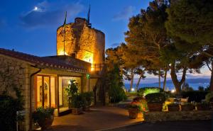 a building with a tower on top of it at night at Boutique Hotel Torre Di Cala Piccola in Porto Santo Stefano
