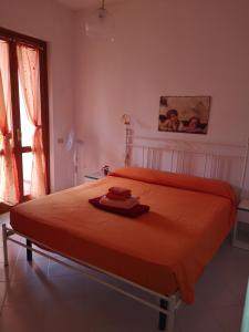 a bedroom with a bed with an orange blanket at Sunny garden house in Villasimius