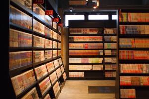 a room with stacks of books on the wall at eeGee STAY Omiya in Saitama