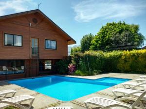a swimming pool in front of a house at Hotel Kernayel in Pucón
