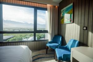 una habitación de hotel con 2 sillas azules y una ventana en Grand Hotel Lili en Taitung