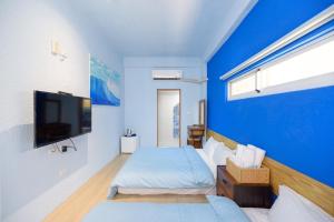 Habitación azul con 2 camas y TV de pantalla plana. en 夏天民宿, en Magong