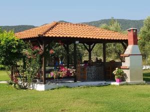 a gazebo with a brick chimney and flowers at Villa Irida in Sarti