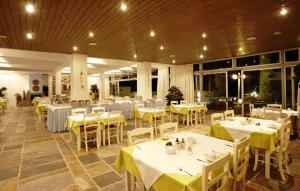 a restaurant with white tables and yellow clothed tables at Apollon Suites in Karistos