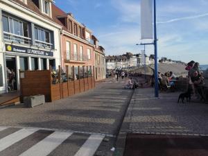 uma rua de calçada com edifícios e pessoas e um cão em Appt face mer em Le Portel