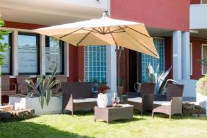 een patio met een parasol, stoelen en een tafel bij Villa Boninsegna in Castel d'Azzano