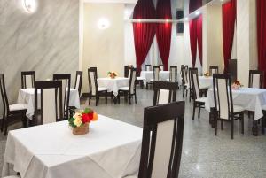 a dining room with white tables and chairs and red curtains at Vila Teleconstructia in Slănic-Moldova