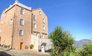 a large brick building with a palm tree in front of it at Gîte Emma in Santo-Pietro-di-Tenda