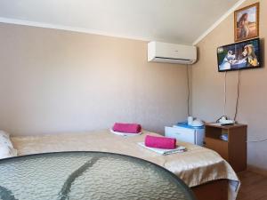 a room with two beds and a tv on the wall at Guest House Komsomolskiy in Anapa