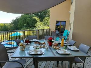 einen Tisch mit Teller mit Lebensmitteln auf einer Terrasse in der Unterkunft Le Grand Noyer in Ambronay