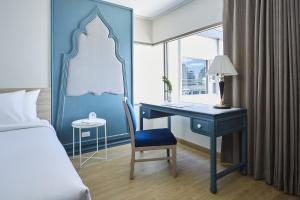 Dormitorio con escritorio con cama y escritorio con silla en 56 Surawong Hotel Bangkok en Bangkok