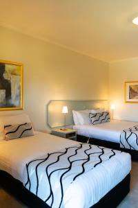 two beds sitting in a room with two lamps at Deniliquin Country Club Motor Inn in Deniliquin