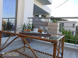 uma mesa de vidro numa varanda com uma mesa e copos em Popis Sea View Apartments em Agia Pelagia