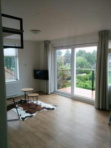 Una sala de estar con una gran ventana y un televisor. en de Pastorie, en Hollum