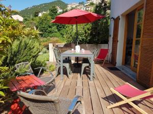 eine Terrasse mit einem Tisch, Stühlen und einem Sonnenschirm in der Unterkunft Côté Lac Tolla in Tolla