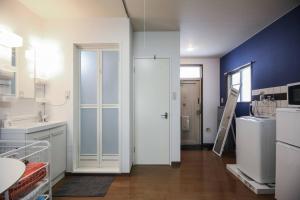 a kitchen with a white refrigerator and a blue wall at 松戸駅ｽｸﾞ 1DK 出張に旅行に Nomad松戸宿019 in Matsudo