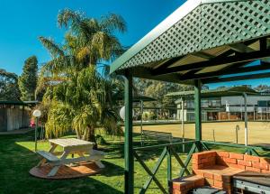 una mesa de picnic y un banco en un parque en Deniliquin Country Club Motor Inn, en Deniliquin