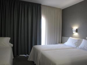 a hotel room with a bed and a window at Hotel Ton in Sanxenxo