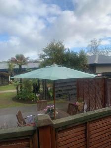 un grand parasol vert assis sur une terrasse en bois dans l'établissement Tarawera River Lodge Motel, à Kawerau