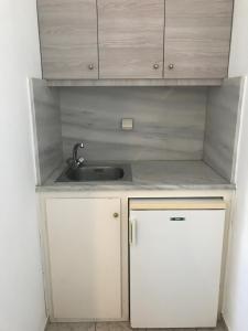 a small kitchen with a sink and white cabinets at Romantika in Platis Gialos