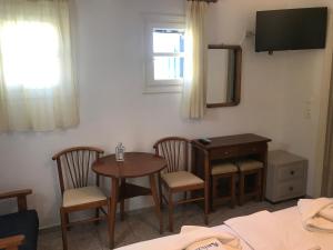 Zimmer mit einem Tisch, Stühlen und einem TV in der Unterkunft Romantika in Platis Gialos