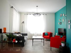 uma sala de estar com um sofá e uma cadeira vermelha em Aux Lagerstroemias em Bergerac