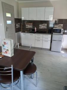 a kitchen with white cabinets and a table and chairs at Gajówka in Radków