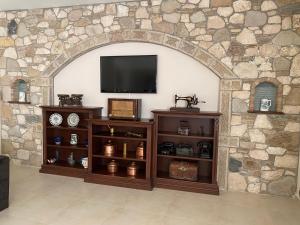 a stone wall with an entertainment center with a television at Thalina Hotel in Marathokampos