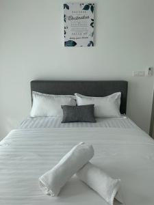 a white bed with white sheets and pillows and a sign at FLYPOD - Blue Sky Apartment 4-5pax , Sutera Avenue in Kota Kinabalu