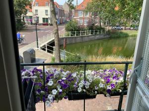 Un balcón con un ramo de flores y un río. en Kromme weele 26, en Middelburg