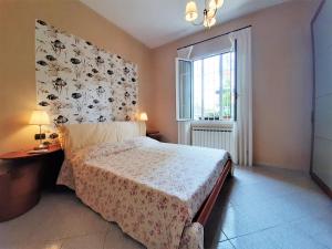 1 dormitorio con 1 cama con cabecero de flores y ventana en Villa la Casetta con giardino a 30 m dal mare, en San Bartolomeo al Mare