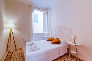 a white bedroom with a bed and a window at Apartment In The Heart Of Sanremo in Sanremo