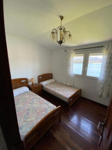 1 dormitorio con 2 camas y lámpara de araña en apartamento con vistas al mar y la montaña, en Santa Marta de Ortigueira