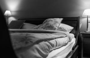 a black and white photo of an unmade bed at Country House Duinhof in De Haan