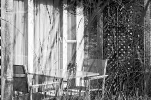 une table en verre et deux chaises assises devant une fenêtre dans l'établissement Country House Duinhof, au Coq