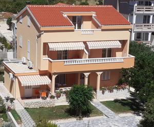 a large house with a red roof at Apartmani Ruža in Novalja
