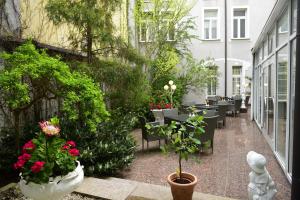 un patio con mesas, sillas, plantas y flores en Hotel Alexandra, en Plauen