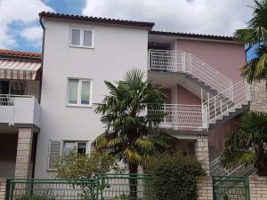 a white building with a palm tree in front of it at Guesthouse Klaric in Rovinj