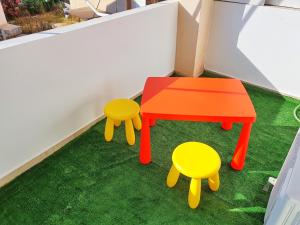 una mesa y dos taburetes en un suelo verde en Gemareia Lodge, en Lefkada
