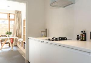 uma cozinha branca com um fogão e uma bancada em The Little Townhouse em Amsterdã