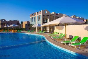 a swimming pool with green lounge chairs and umbrellas at Green Leaves Hotel in Dawwār Abū Duray‘ah ‘Abd al Karīm