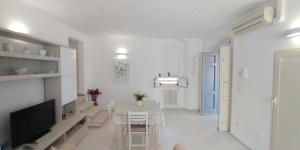 a white living room with a table and a tv at Torre Camarda in Bernalda