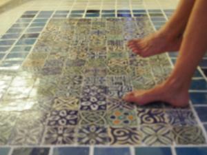una persona parada en el suelo de un baño de azulejos en Casas de la Judería, judería nueva, en Cáceres