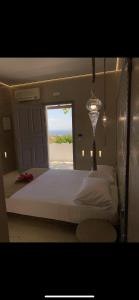 Schlafzimmer mit einem großen weißen Bett und einem Fenster in der Unterkunft Blue Sky in Chora, Ios